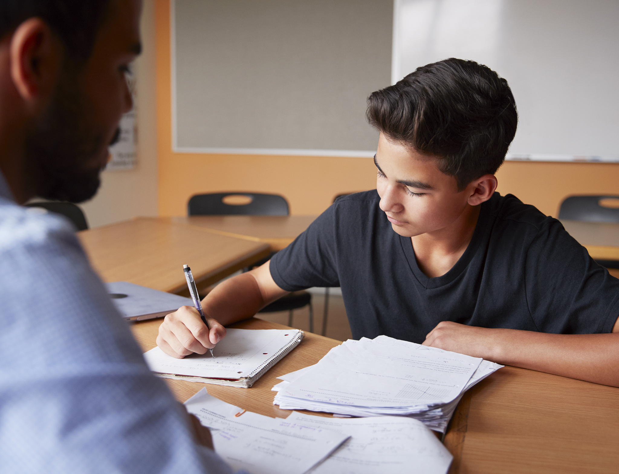 High School Tutor Giving Male Student One To One Tuition At Desk