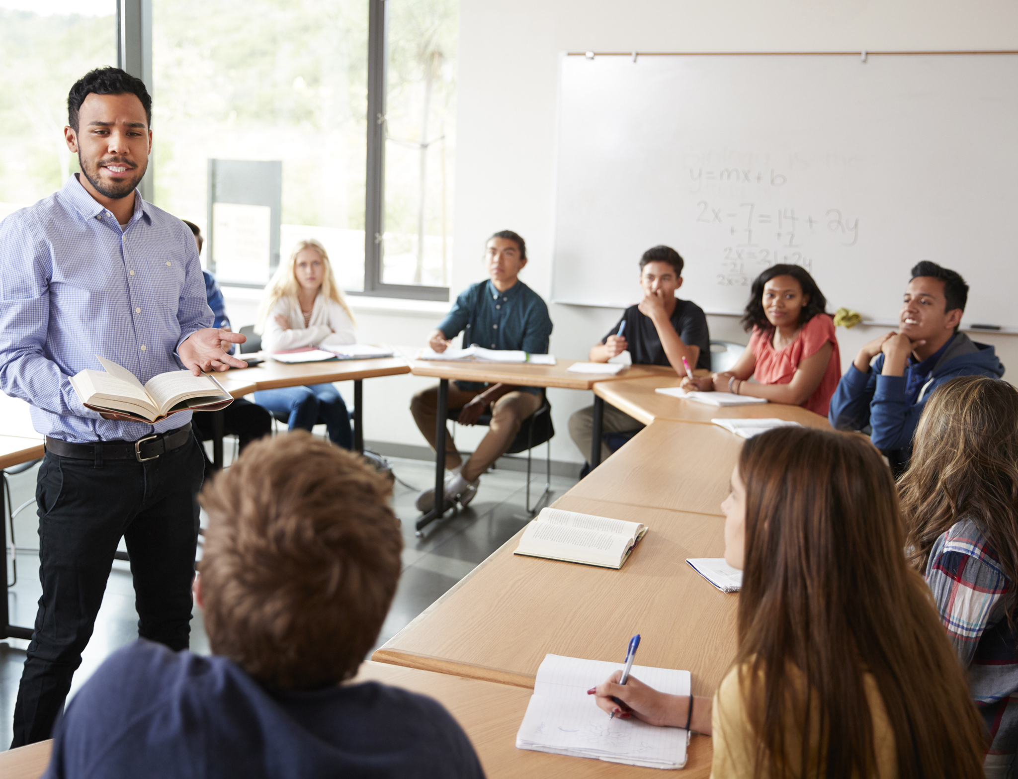 Male High School Tutor With Pupils Sitting At Table Teaching Maths Class